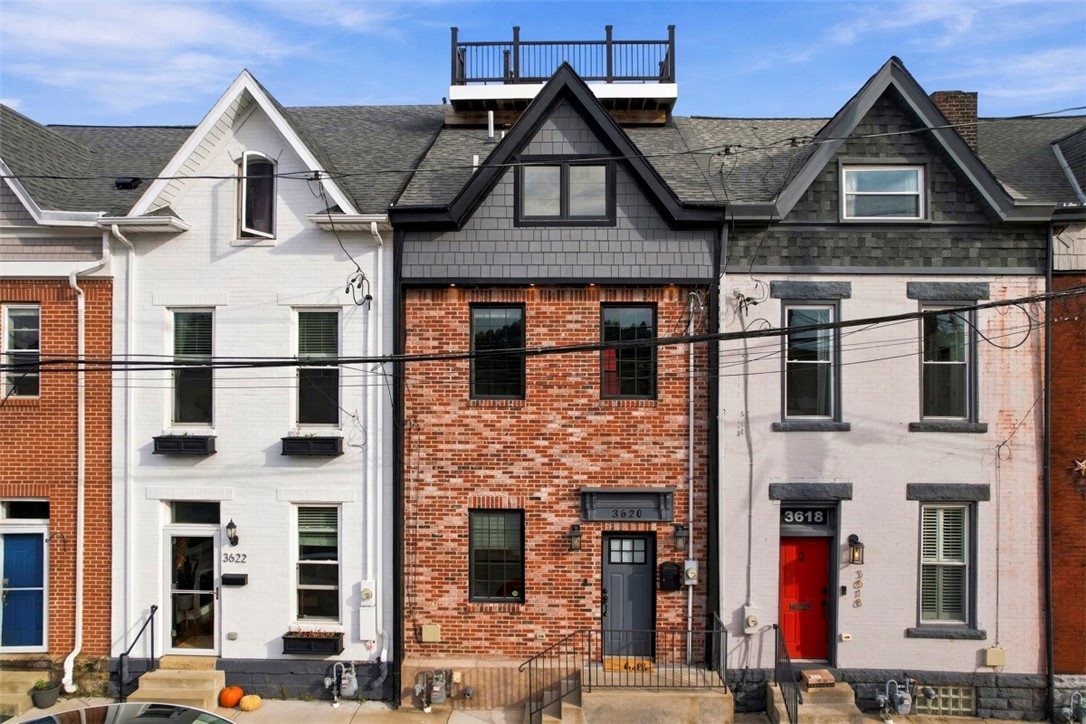 Attached urban houses with brick and painted facades, peaked roofs, and a rooftop deck.