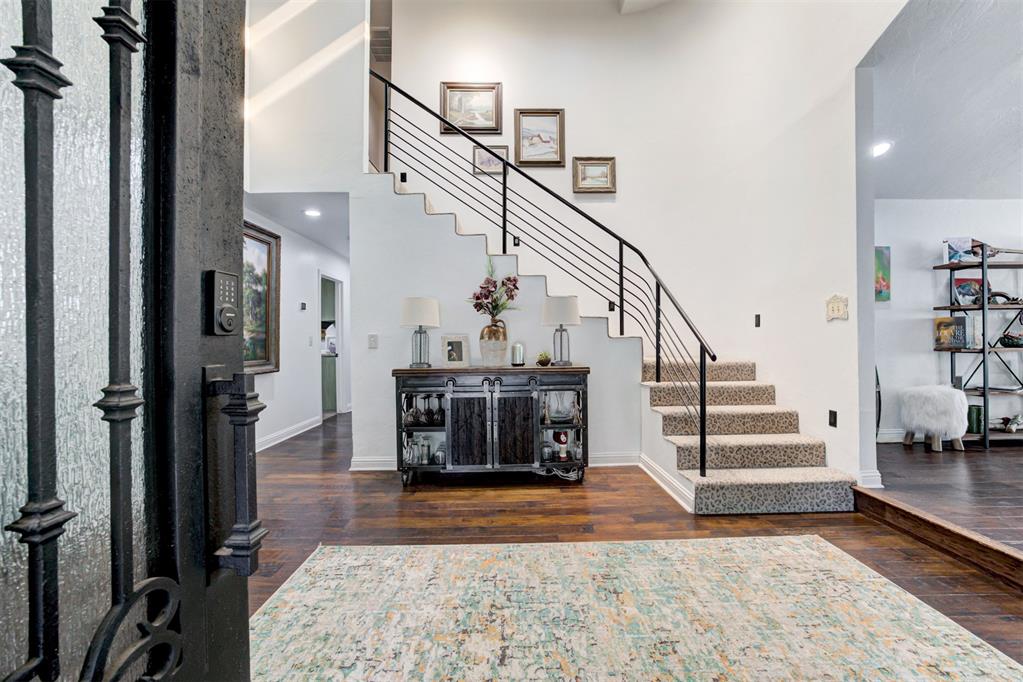 Foyer with a black iron front door, staircase, and console table beneath the stairs.