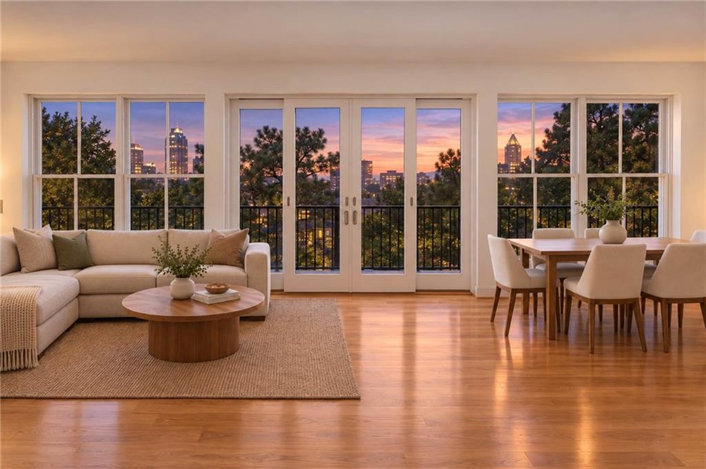 Living and dining room with floor-to-ceiling windows overlooking the city at sunset.