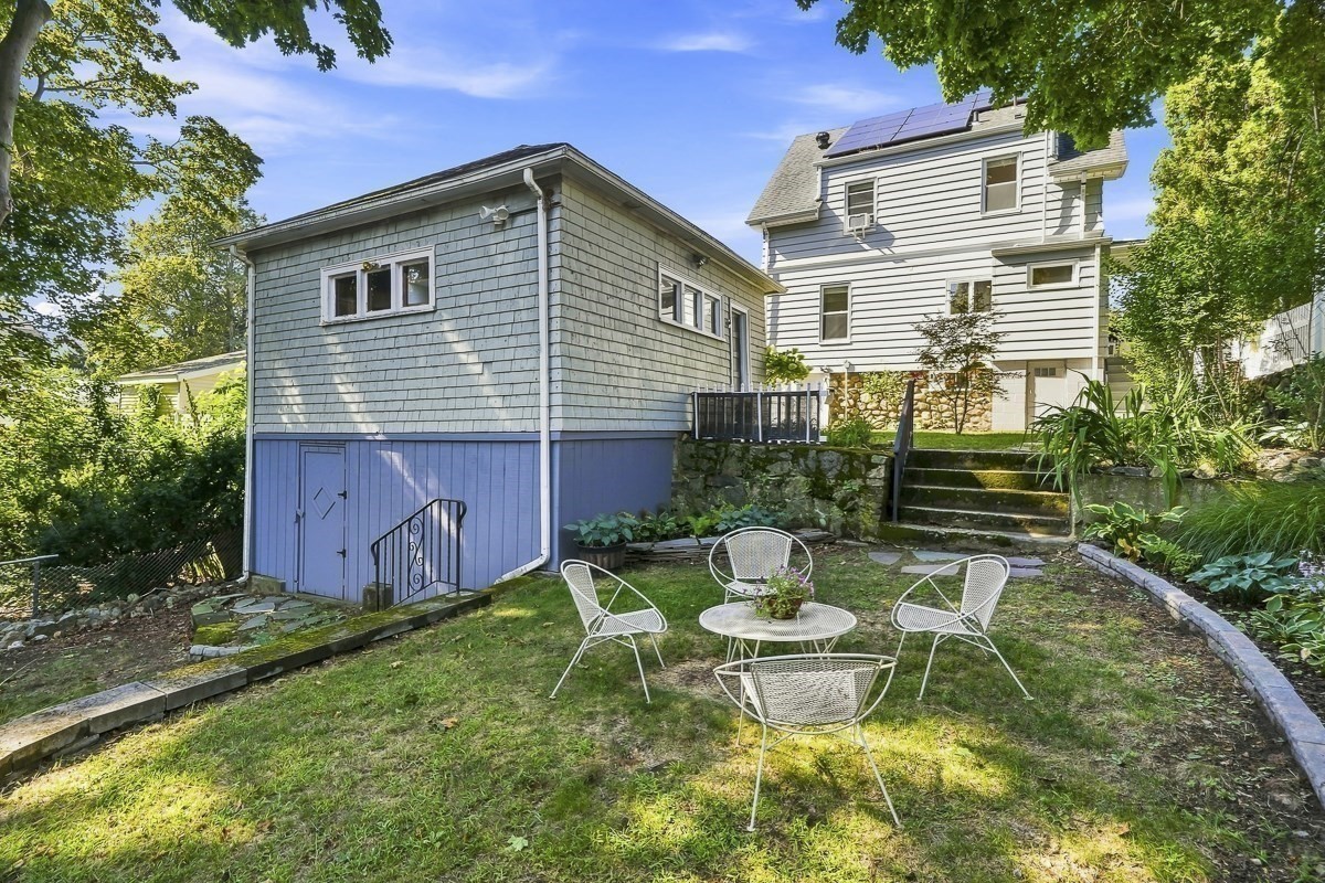 Rear of a two-story house with rooftop solar panels and a garden seating area.