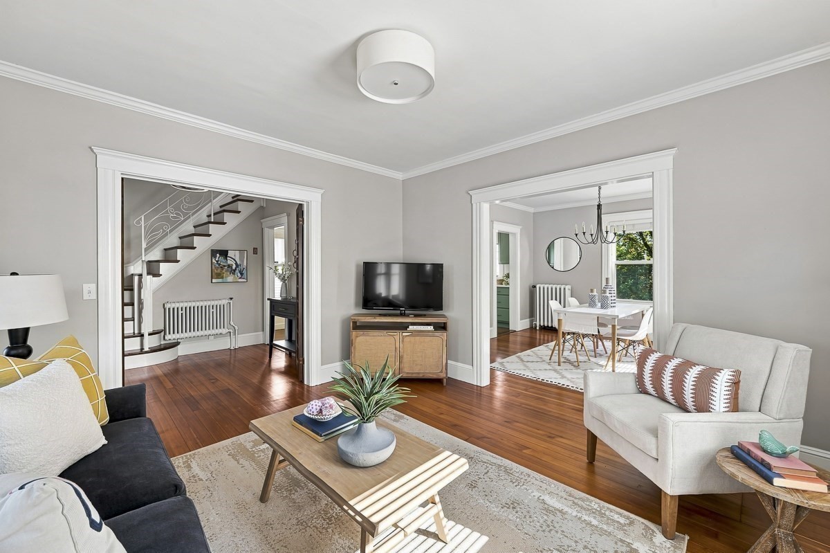 Living room with polished hardwood floors, a central coffee table, and open views to the staircase and dining room.