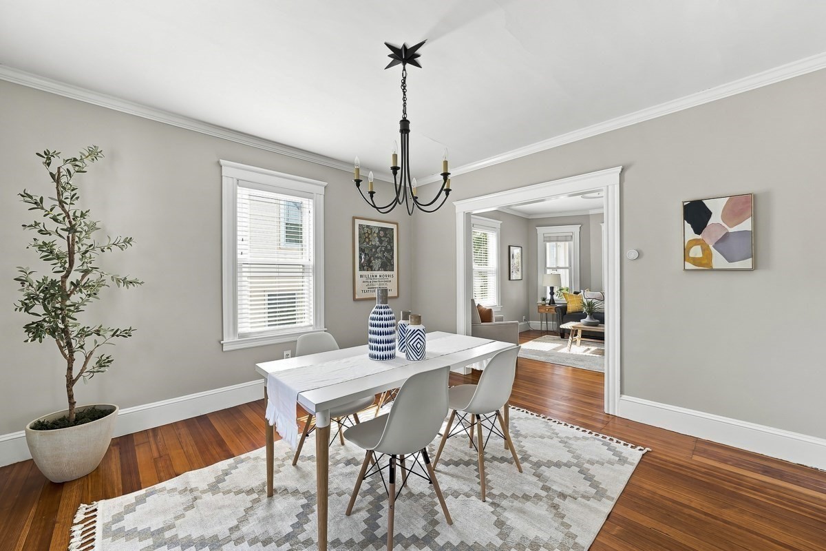 Dining room with a white table, patterned rug, chandelier, and doorway to the living room.