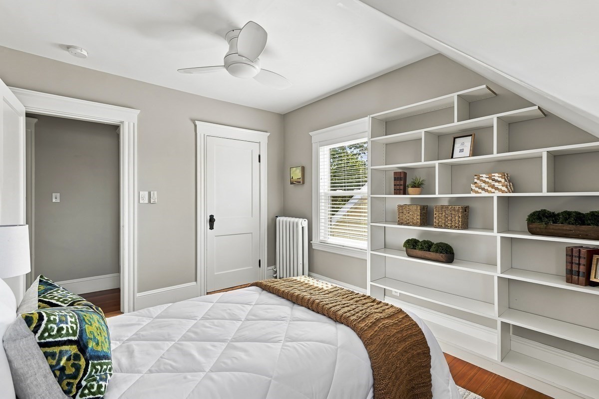 Bedroom with built-in white shelving, a white bed, and colorful patterned pillows.