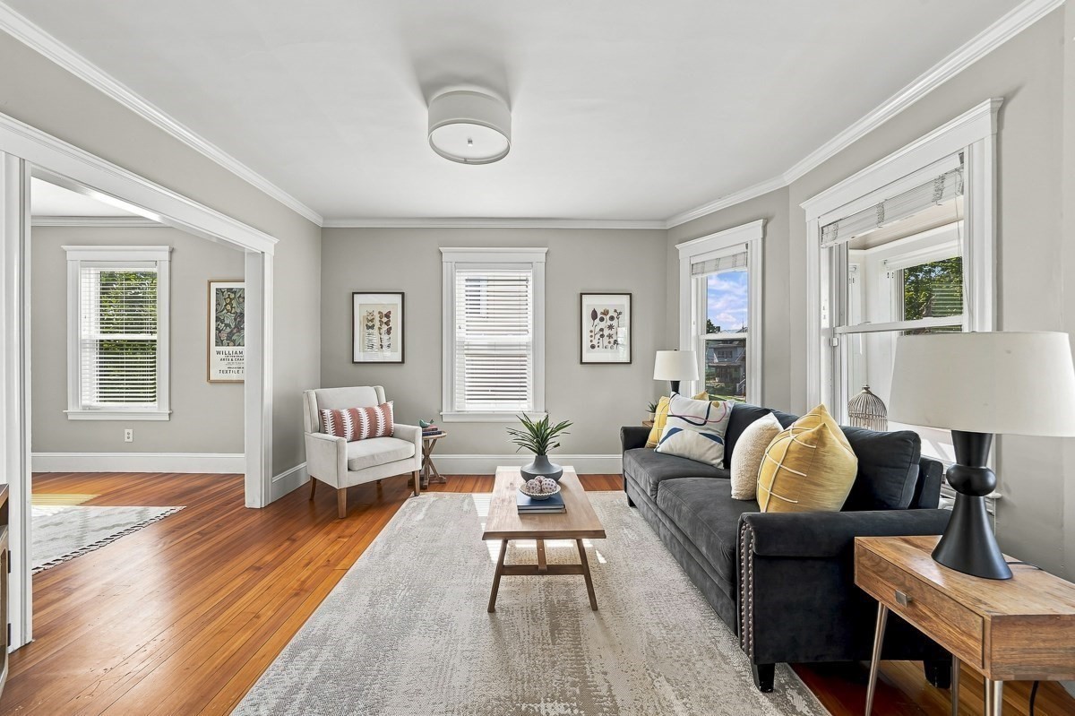 Living room with a dark sofa, large windows, and polished hardwood floors.