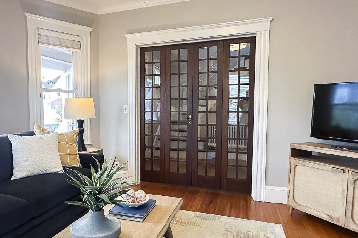 Living room with glass-paneled double doors, a dark sofa, and hardwood floors.