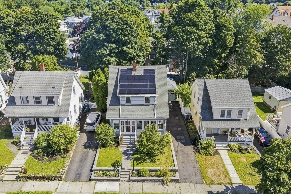 Aerial view of a two-story home with rooftop solar panels and a landscaped front yard.