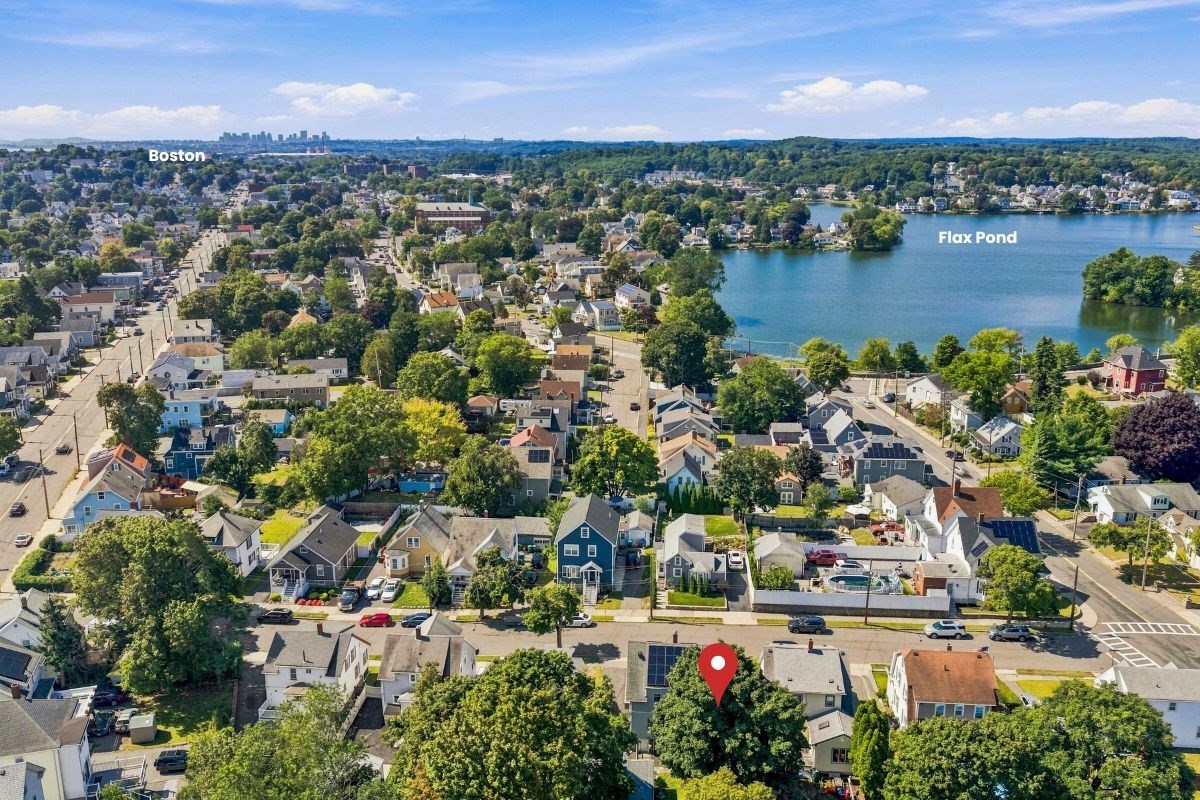 Aerial neighborhood view with Flax Pond, distant Boston skyline, and a red pin marking a home.