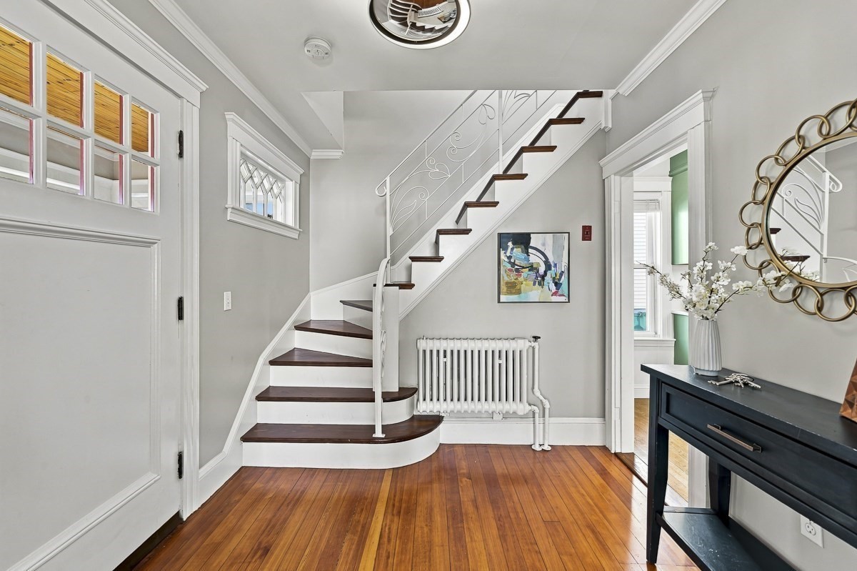 Entry foyer with a curved staircase, decorative white railing, and polished hardwood floors.