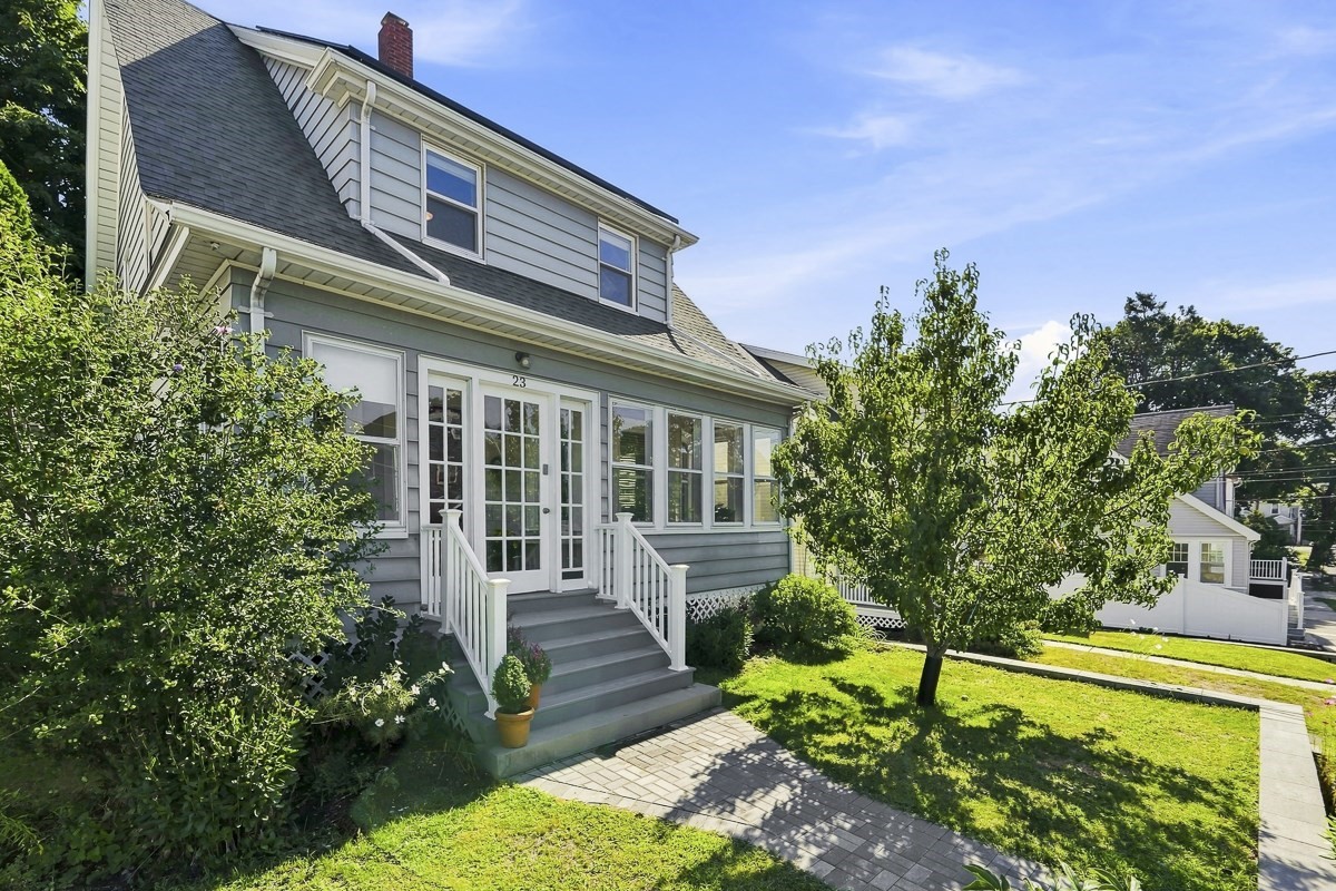 Gray two-story house with white trim, a glass-paneled entry, front steps, and a paver walkway.