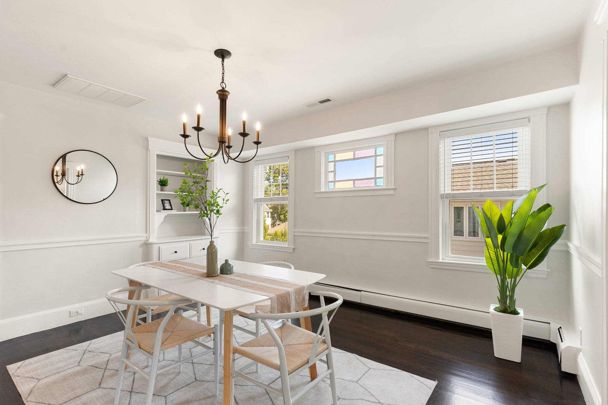 Staged dining room with a white table, chandelier, built-in shelves, and large windows.