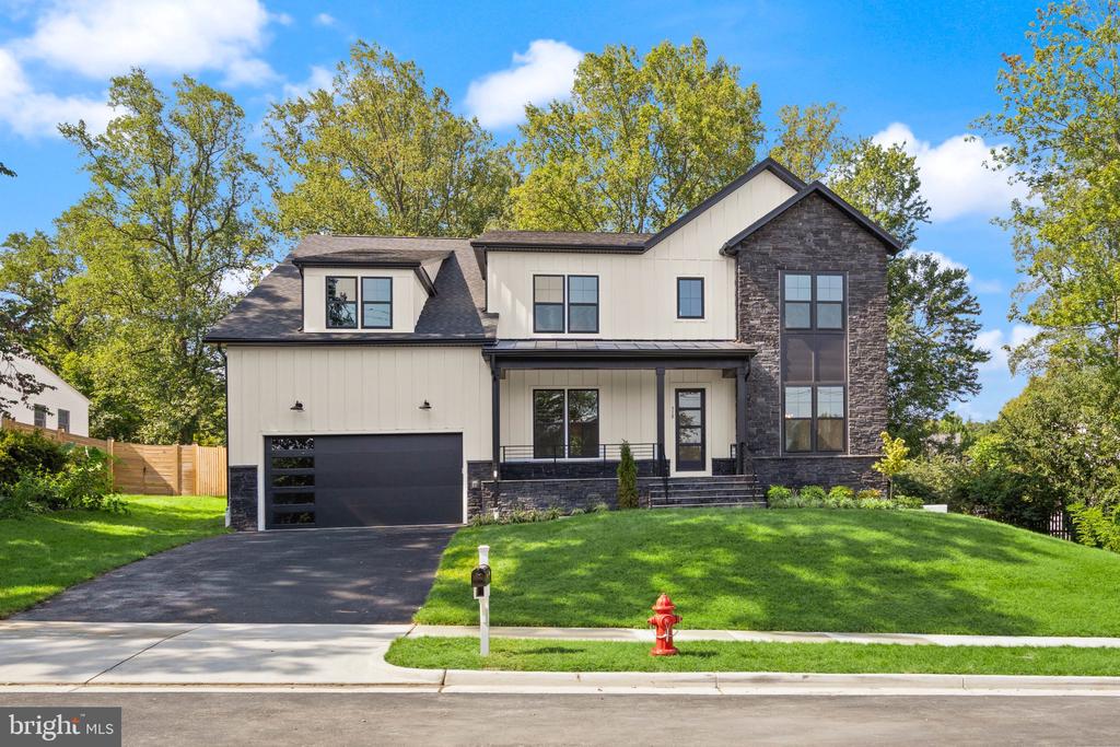 Modern two-story home with a stone facade, attached garage, and broad green lawn.
