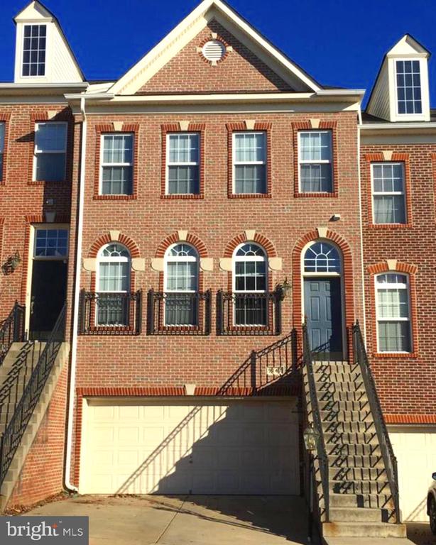 Red-brick townhouse with arched windows, a garage, and stairs to the front entry.
