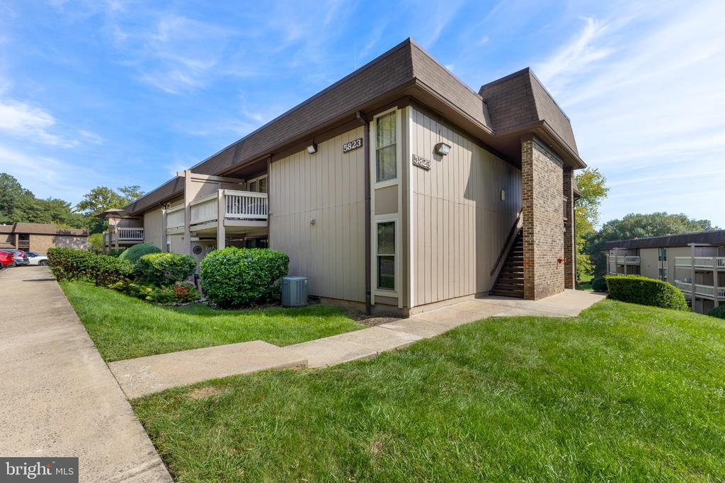 Multi-unit residential building with exterior stairs, balconies, and a landscaped lawn.
