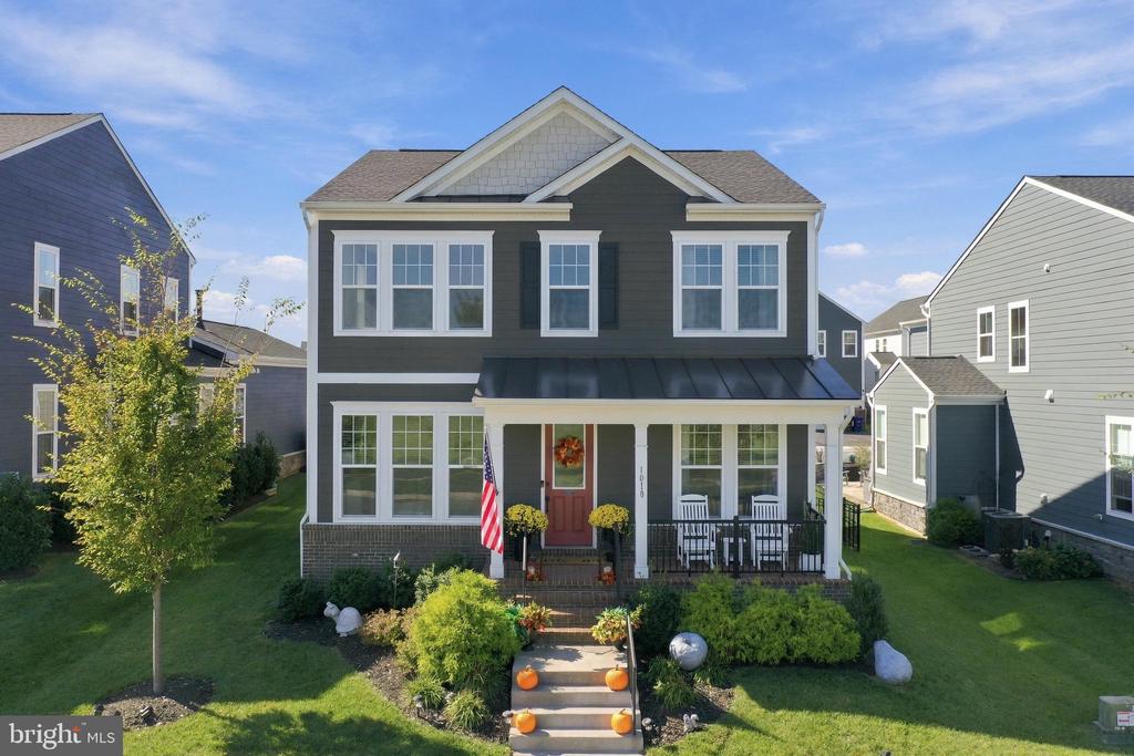 Two-story gray house with a red front door, covered porch, and landscaped front yard.