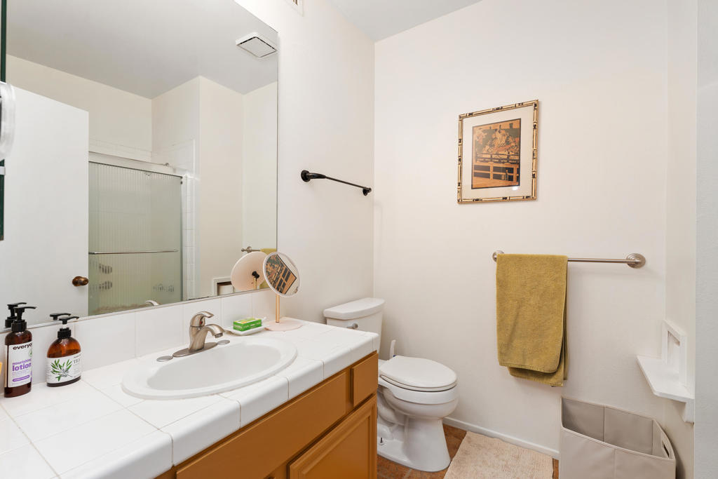 Bathroom with a tiled vanity, oval sink, frosted-glass shower, and towel bar.