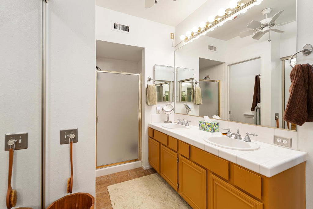 Bathroom with a double-sink vanity, large mirror, and glass-enclosed shower.