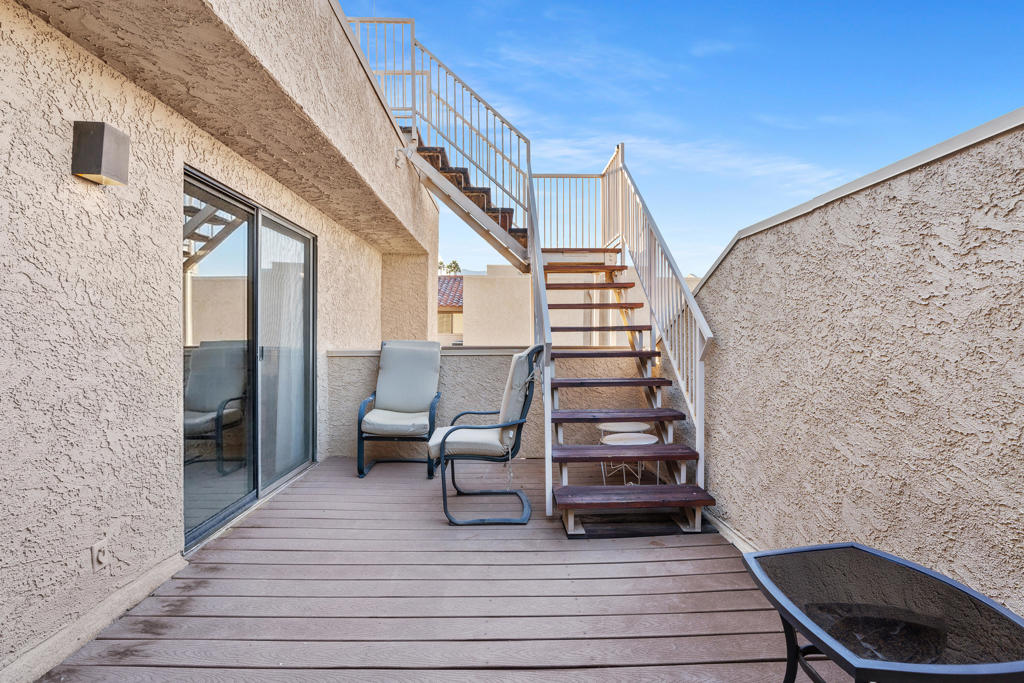 Patio with two chairs and stairs leading to an upper level.