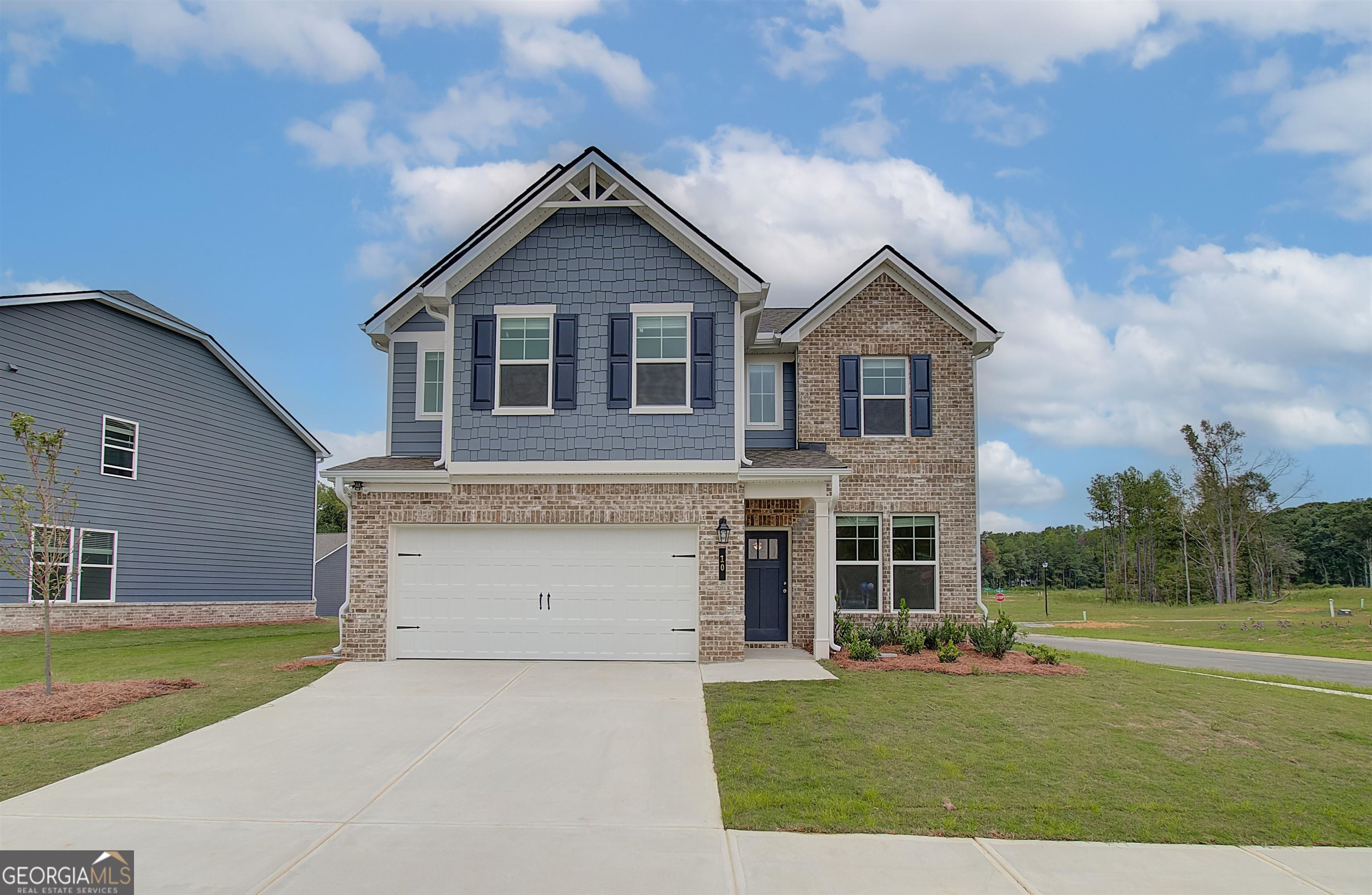 Two-story brick and blue-gray house with a two-car garage and wide concrete driveway.