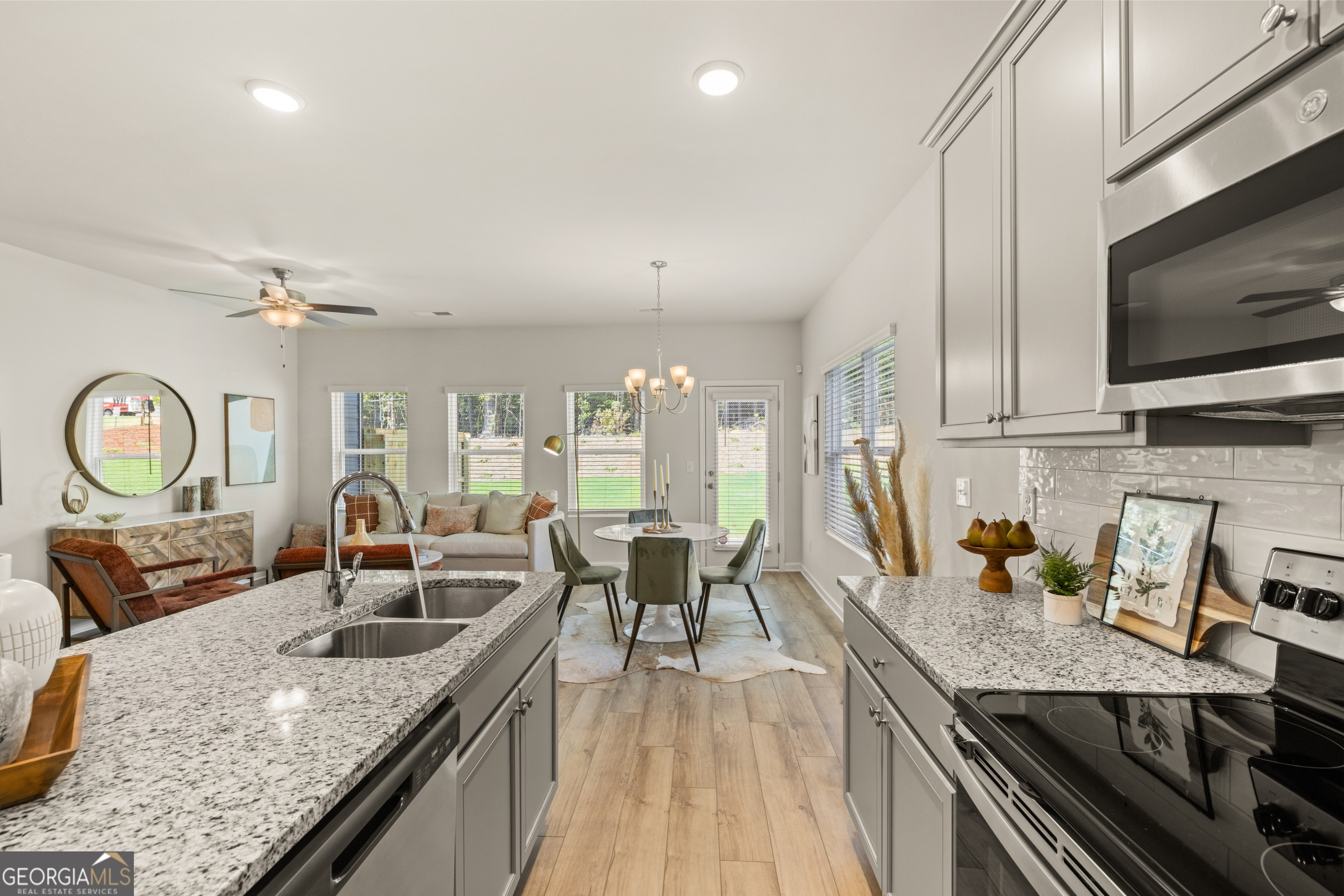 Staged kitchen with granite counters opening onto a dining area and living room.