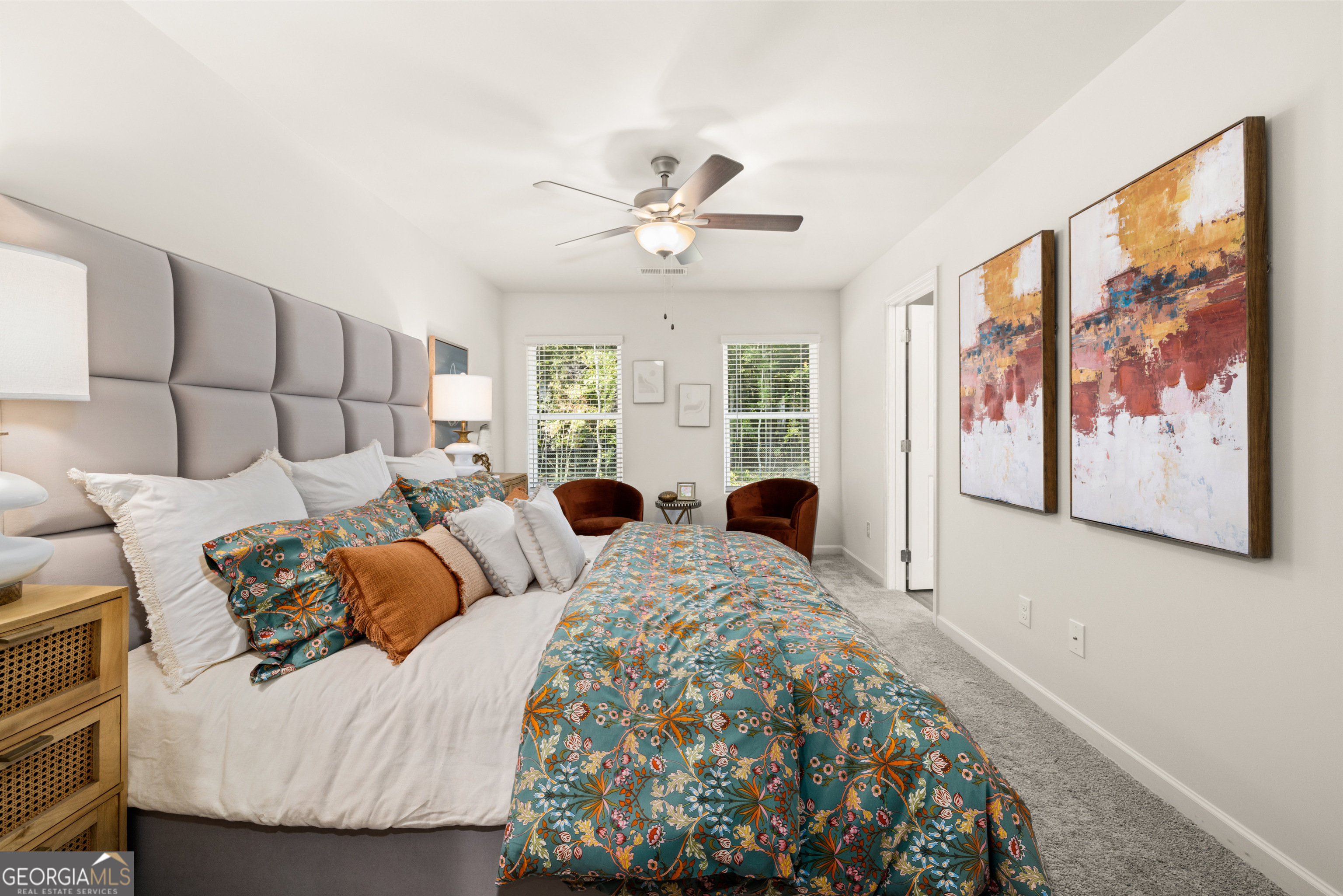 Furnished bedroom with teal floral bedding, a tall upholstered headboard, and abstract wall art.