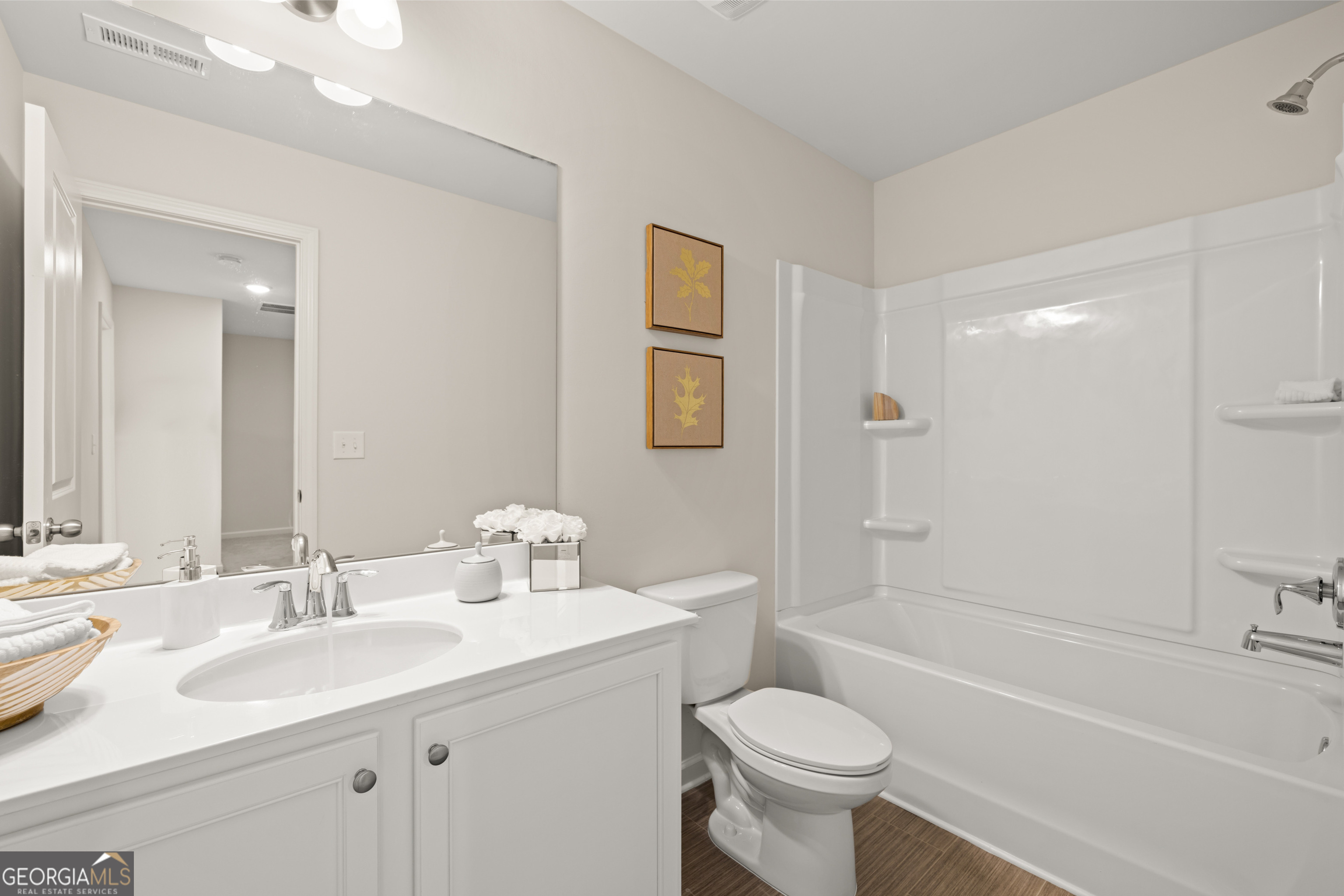 Bathroom with white vanity, toilet, and bathtub with a built-in shower surround.