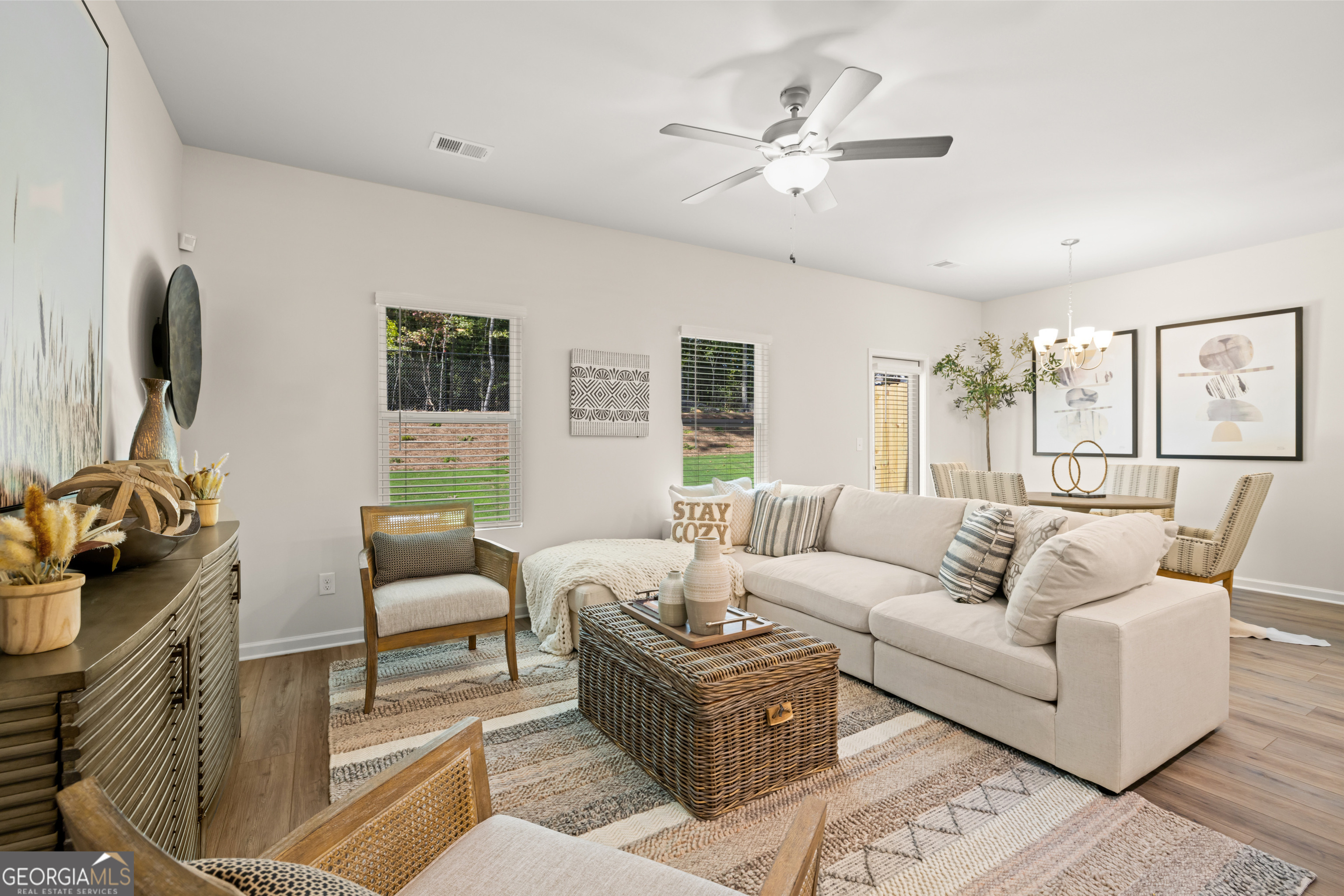 Living room with a cream sectional, woven coffee table, patterned rug, and dining area.