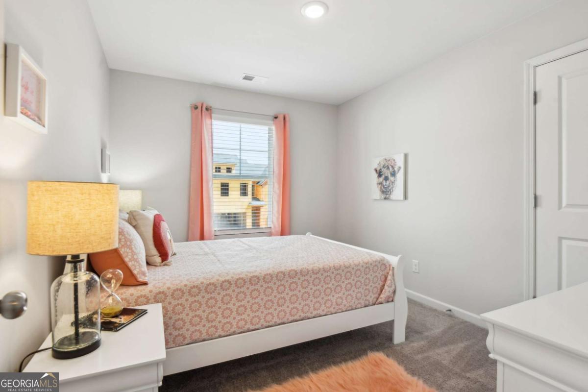 Furnished bedroom with pink patterned bedding, coral curtains, and a white desk.