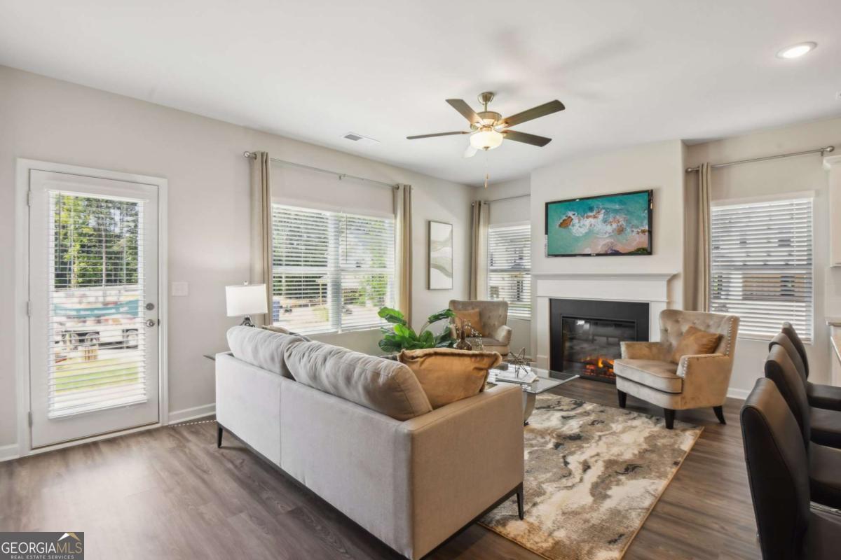 Furnished living room with a gray sofa, fireplace, and large windows.