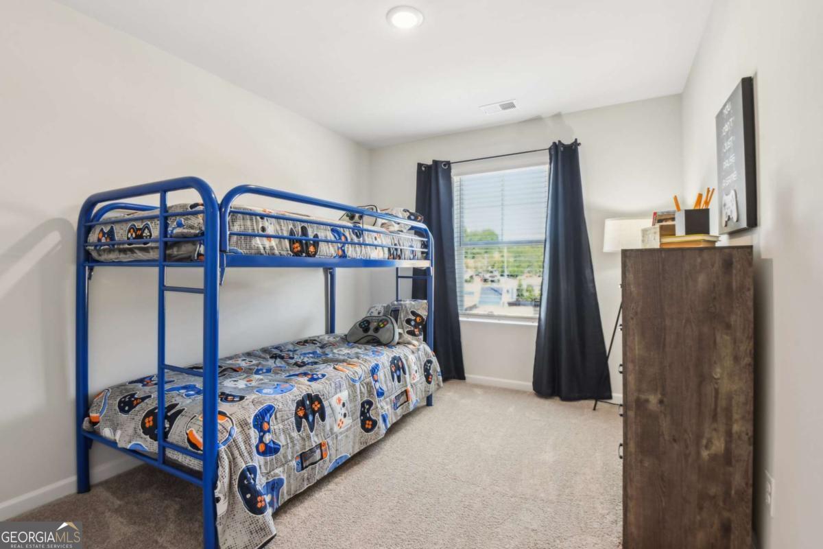 Bedroom with a blue metal bunk bed, patterned bedding, and a window framed by dark curtains.