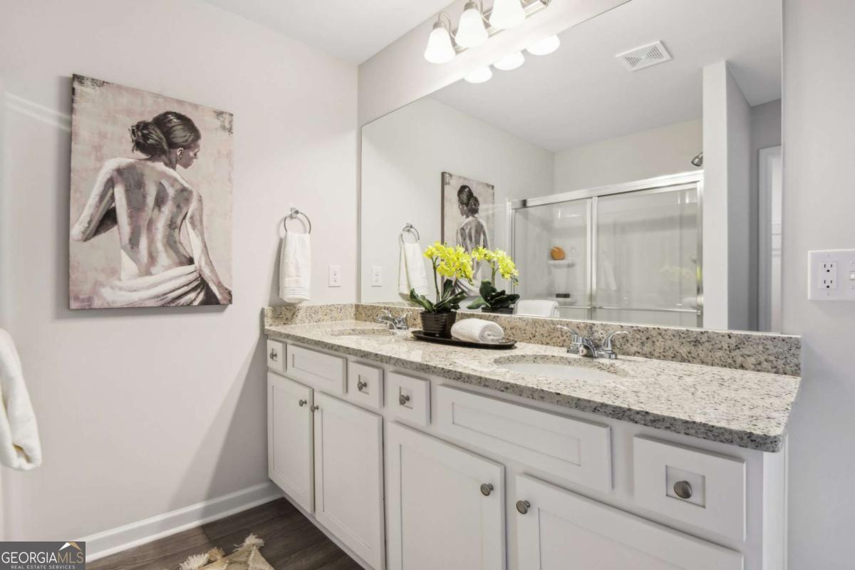 Bathroom with a long white double vanity, granite countertop, and large mirror.