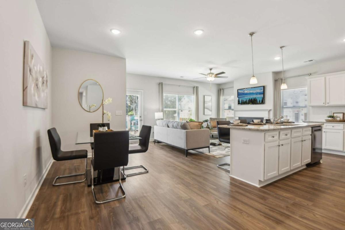 Open-plan living, dining, and kitchen area with a large white island and wood-look floors.
