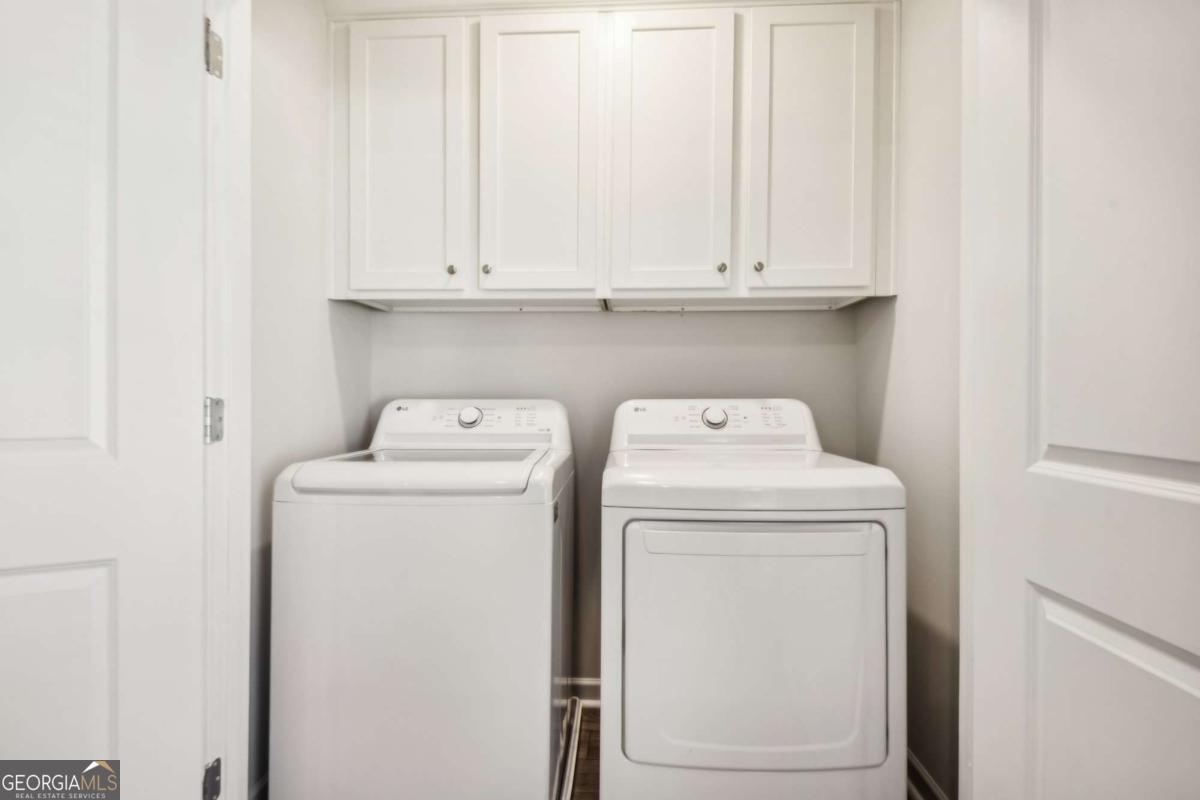 Laundry room with a top-load washer, front-load dryer, and white cabinets.