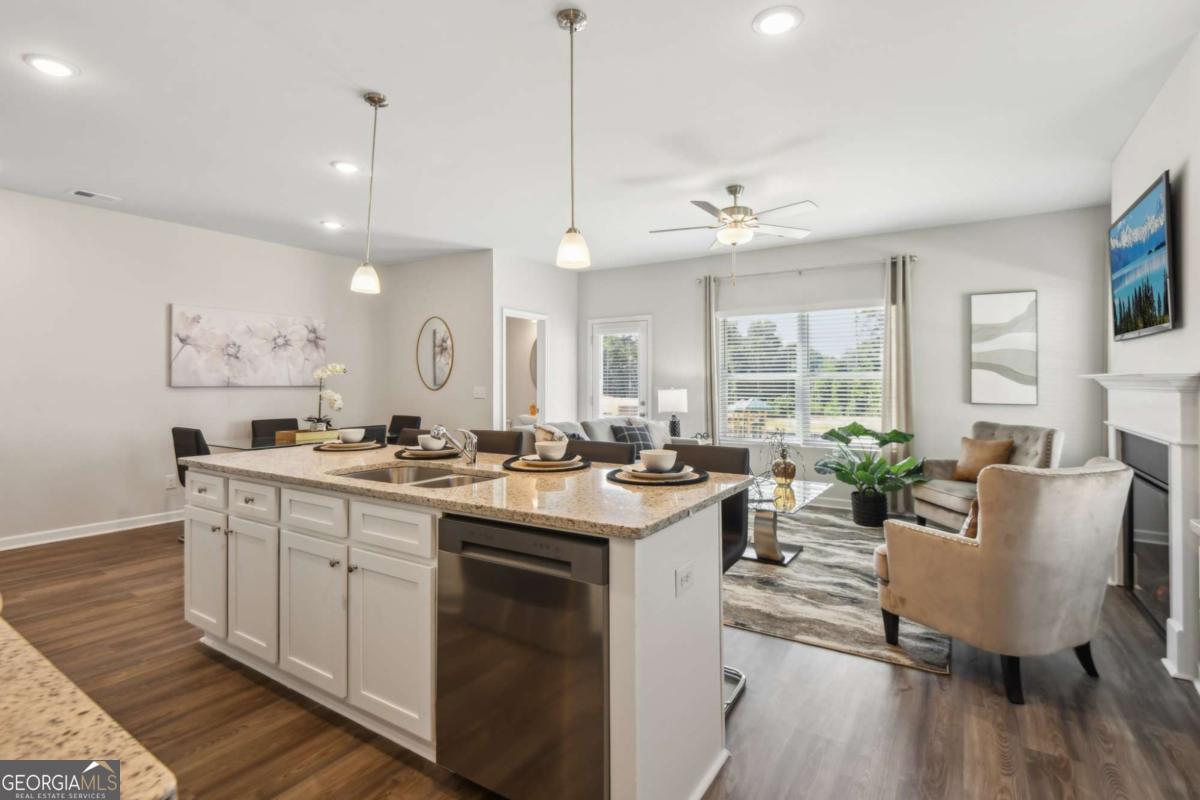 Open-plan kitchen with a large stone-topped island, white cabinets, and adjoining living area.