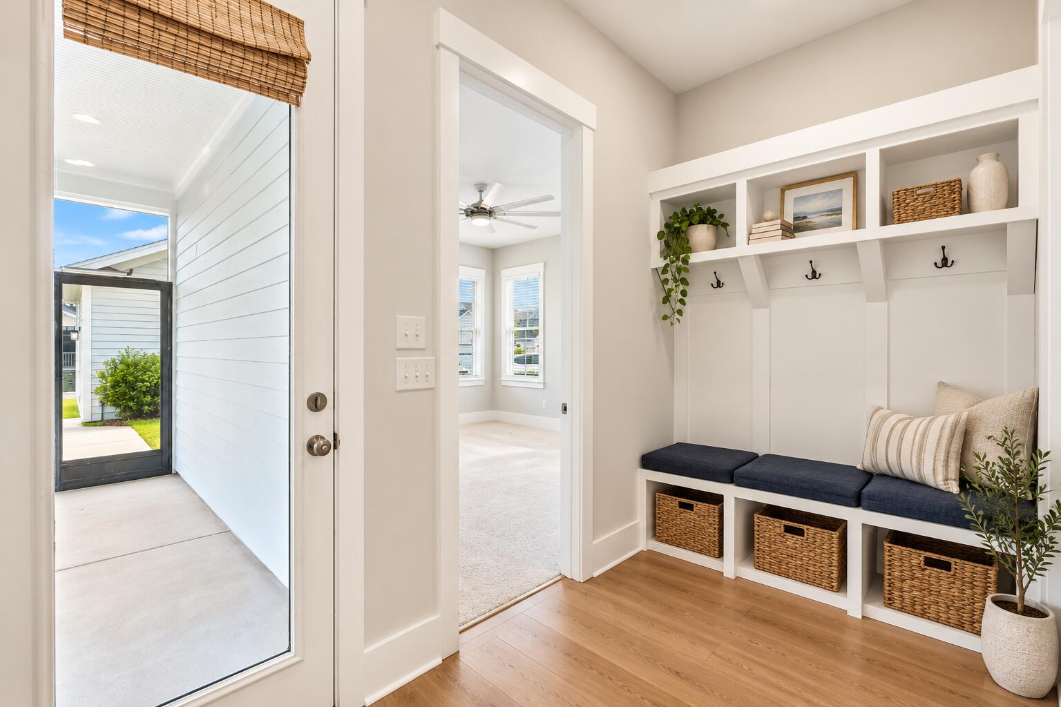 Entryway with a built-in mudroom bench, white cubbies, woven baskets, and a glass exterior door.