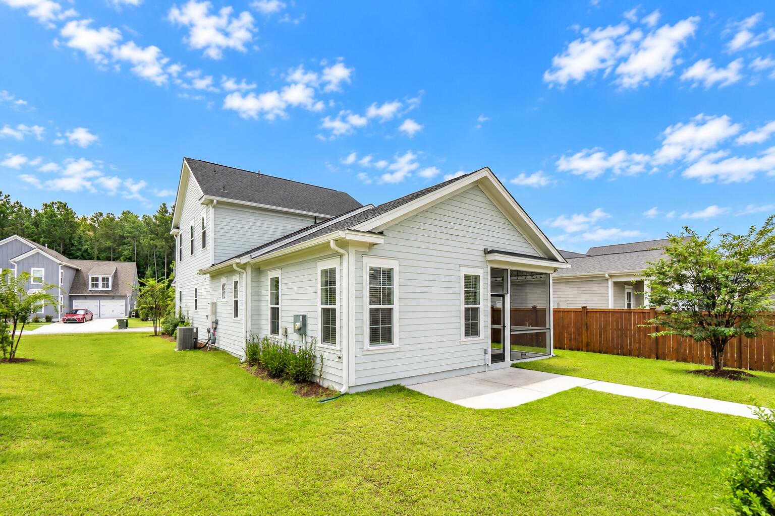 Light-colored two-story home with a screened porch and fenced backyard.
