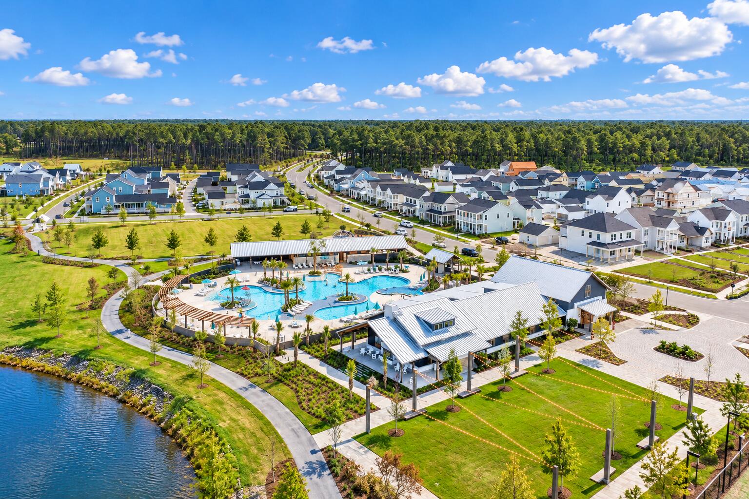 Aerial view of a neighborhood with a large community pool, clubhouse, and pond.