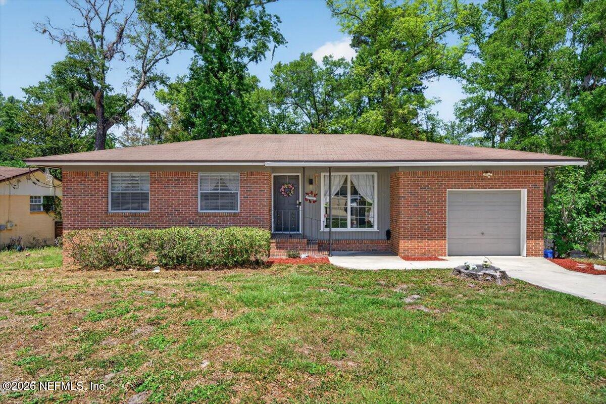 Single-story brick ranch with an attached garage, front lawn, and mature trees.