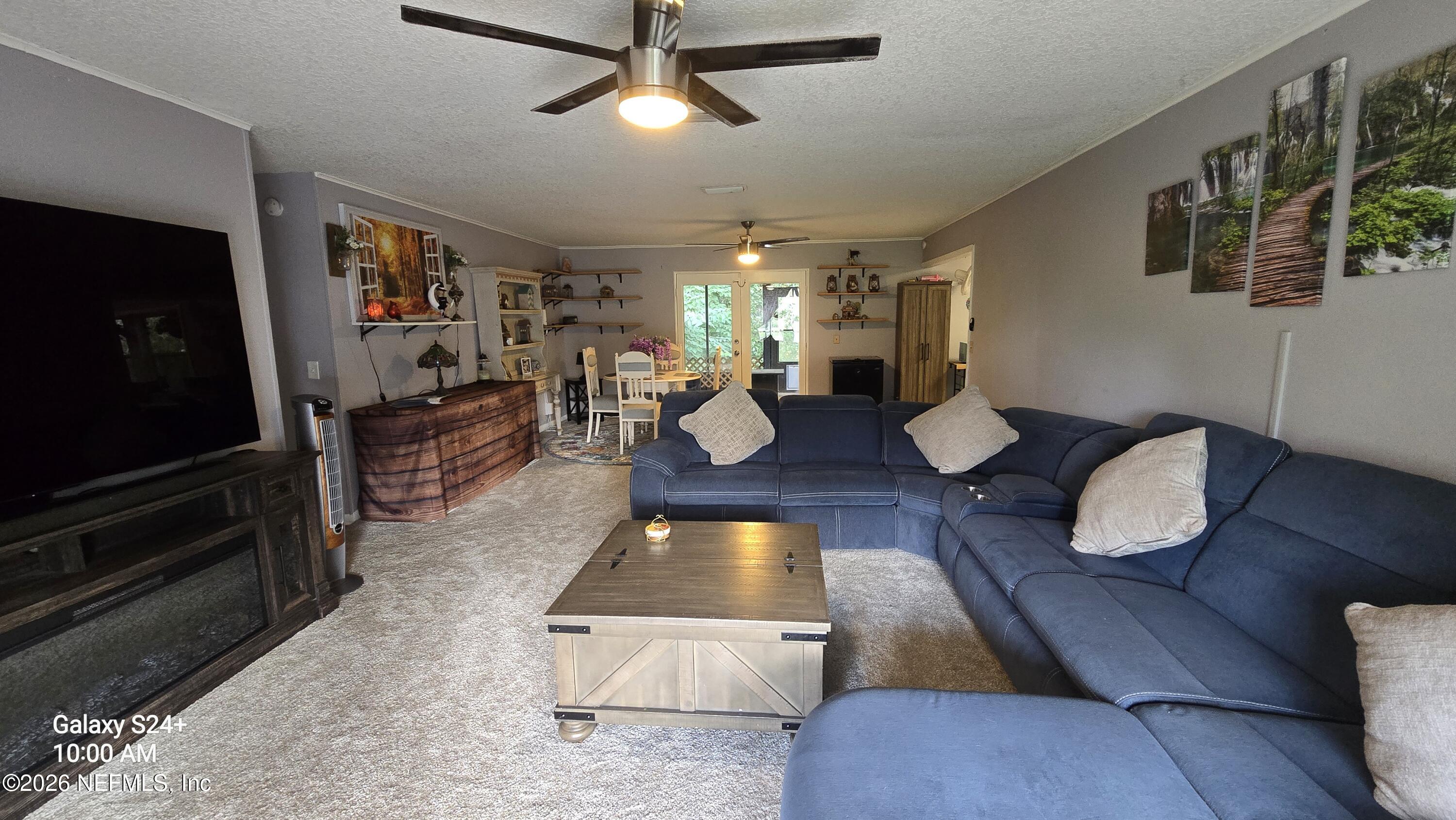 Living room with a navy sectional, wooden coffee table, and glass doors opening to greenery.