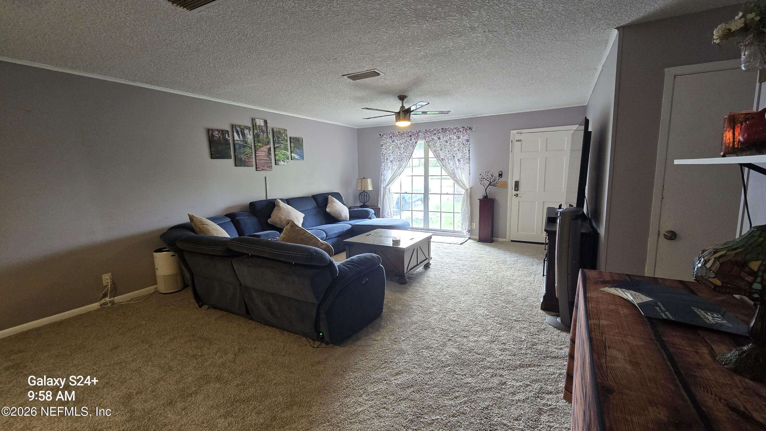 Furnished living room with a blue sectional facing a bright window and front door.