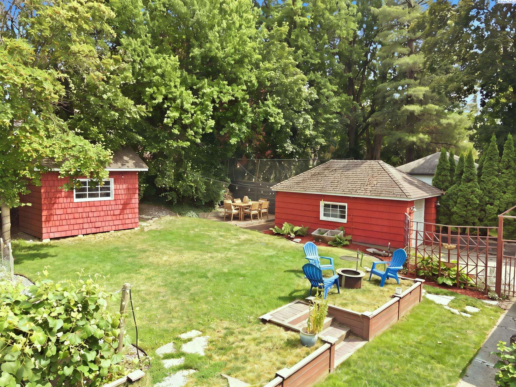 Backyard lawn with raised garden beds, blue chairs and a red shed