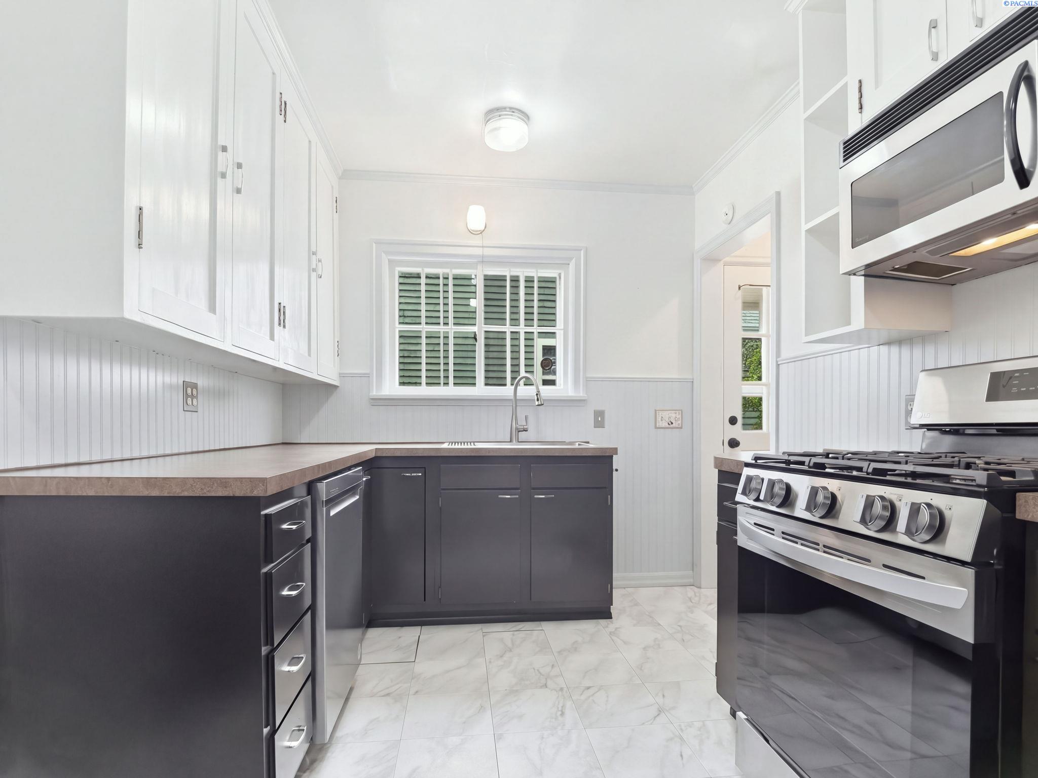 Kitchen with white upper cabinets, dark lower cabinets and a stainless gas range