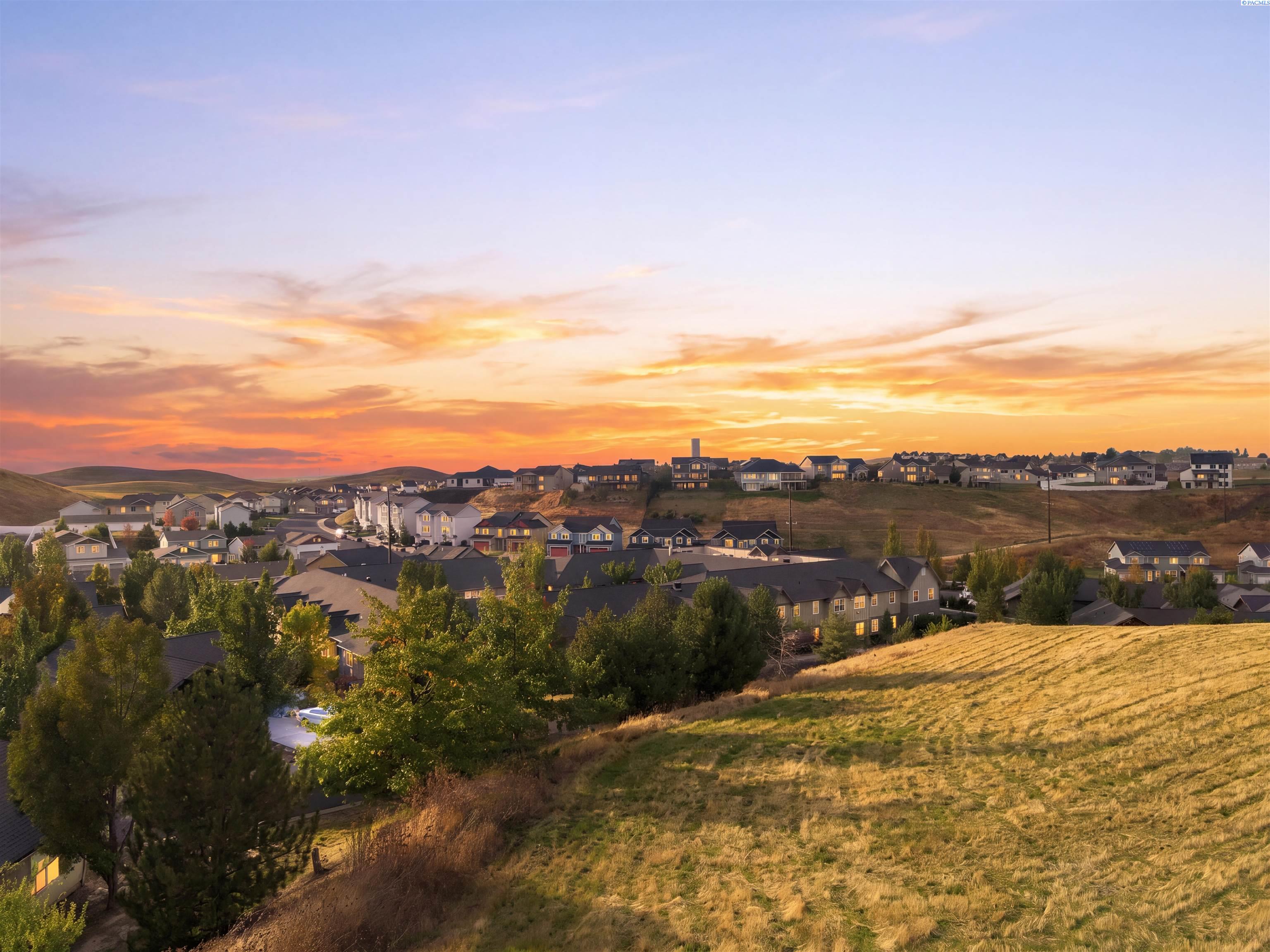 Evening view from the grassy slope across homes toward the horizon
