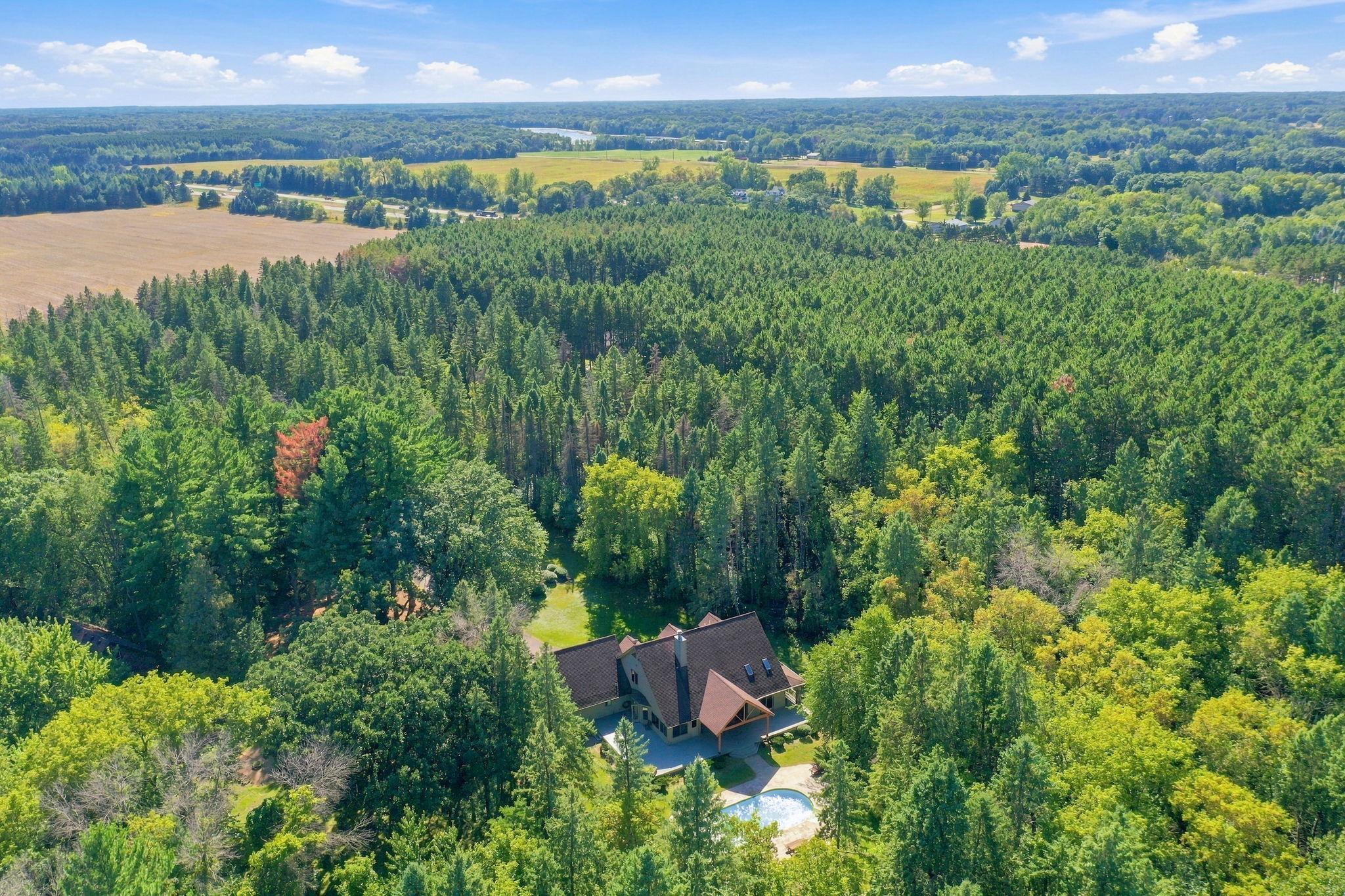 Aerial view of a wooded property with a house and swimming pool.