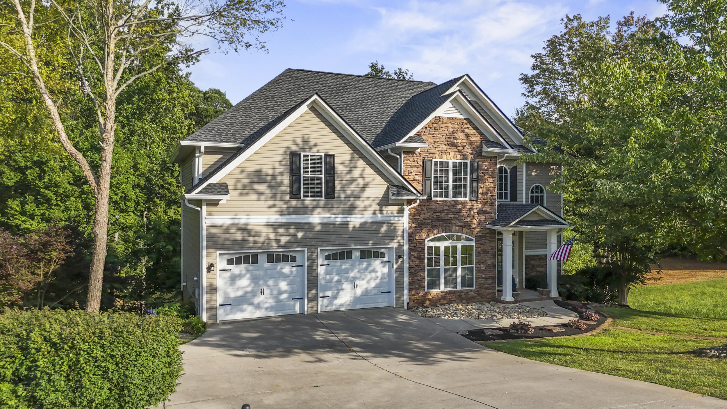 Two-story home with stone and beige siding, a covered entry, and a double garage.
