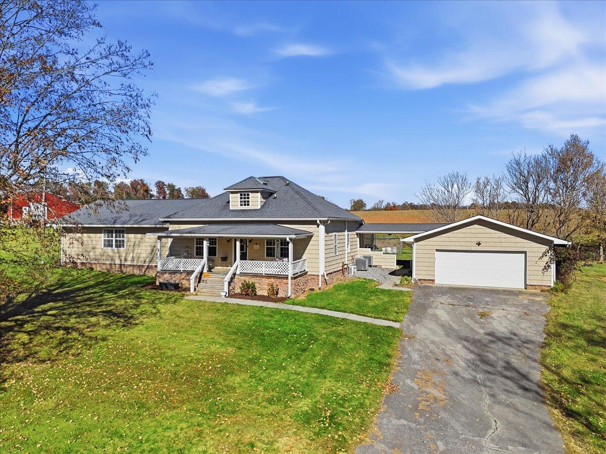 Tan single-story home with a covered porch, detached garage, and broad lawn.