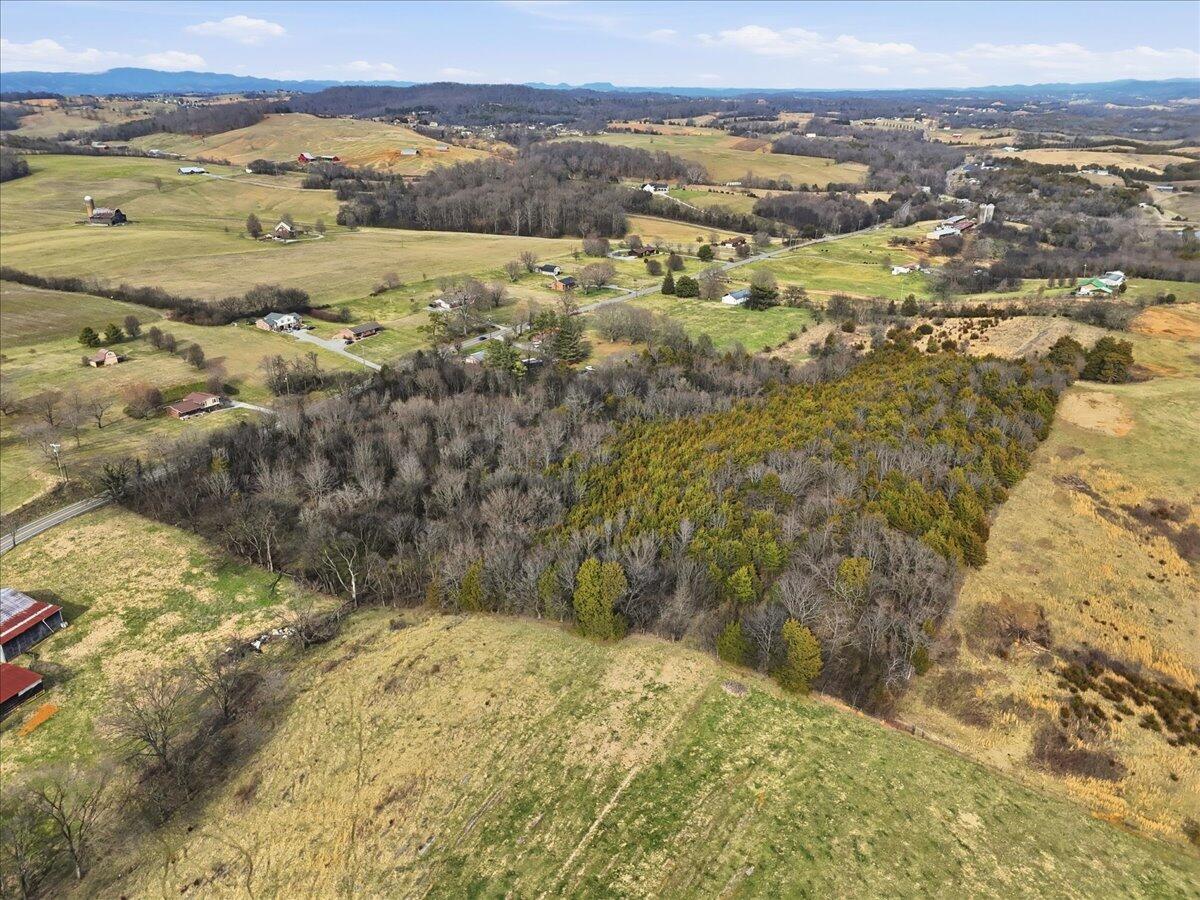 Aerial view of rolling fields and wooded land, with farms and distant mountain ridges.