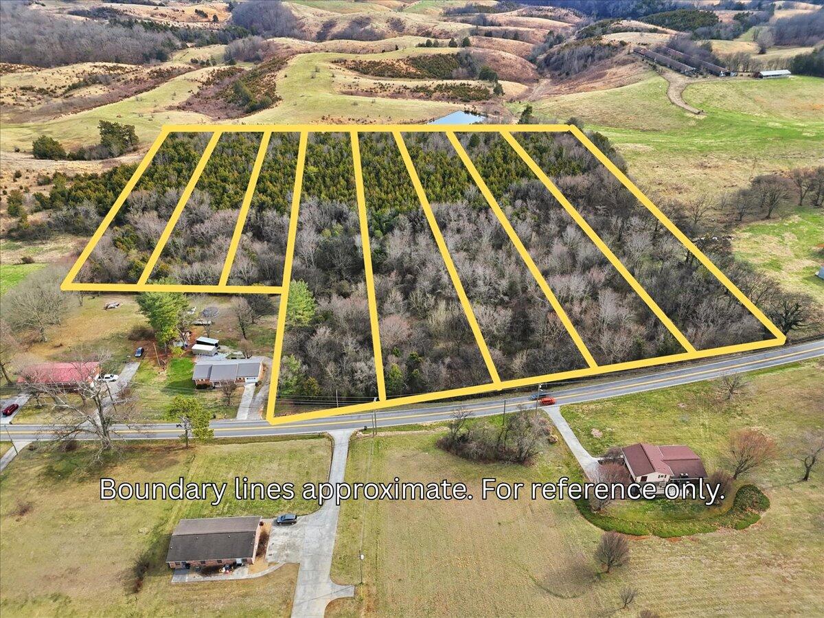 Aerial view of wooded acreage outlined by yellow approximate boundary lines, with road frontage.