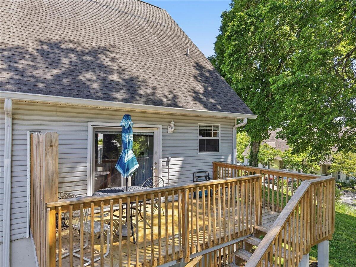 Elevated wooden deck with railings, stairs, patio furniture, and a blue striped umbrella.