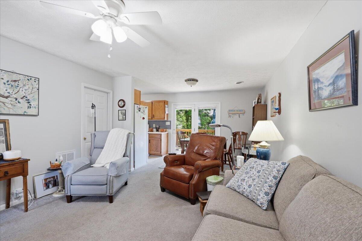 Furnished living room with a brown leather armchair, pale blue recliner, and glass doors opening to greenery.