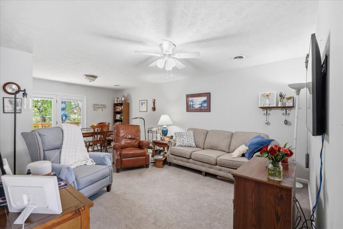 Living room with a gray sofa, blue armchairs, and glass doors opening to a deck.